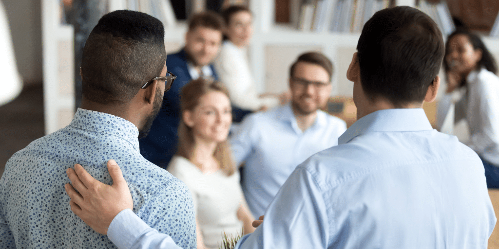 A diverse group of professionals greeting a new employee, who is being introduced by a leader in the office.